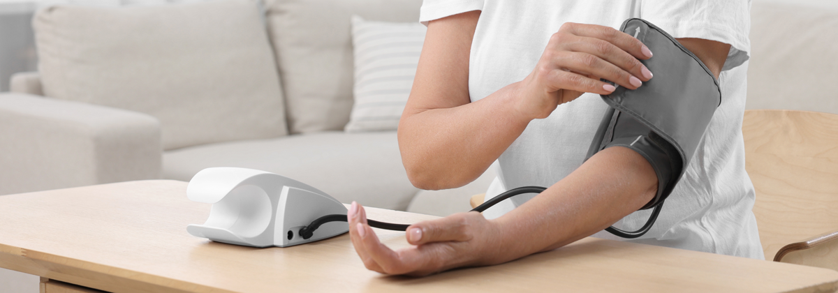 Kobieta wykonuje badanie ciśnienia tętniczego, zakłada mankiet.