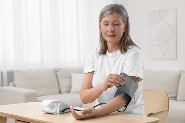 Kobieta wykonuje badanie ciśnienia tętniczego, zakłada mankiet.